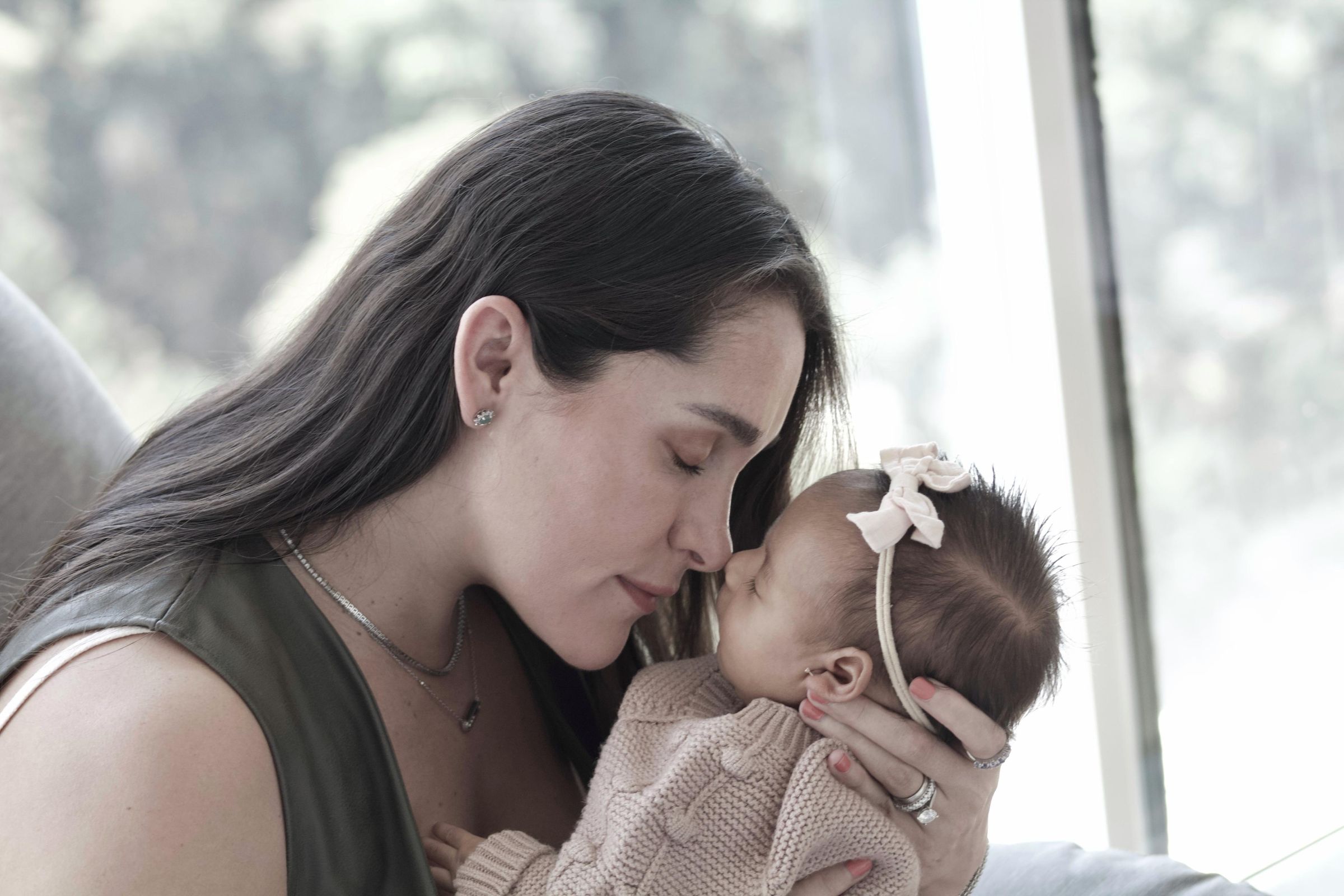 A mother holding her young daughter in soft window light