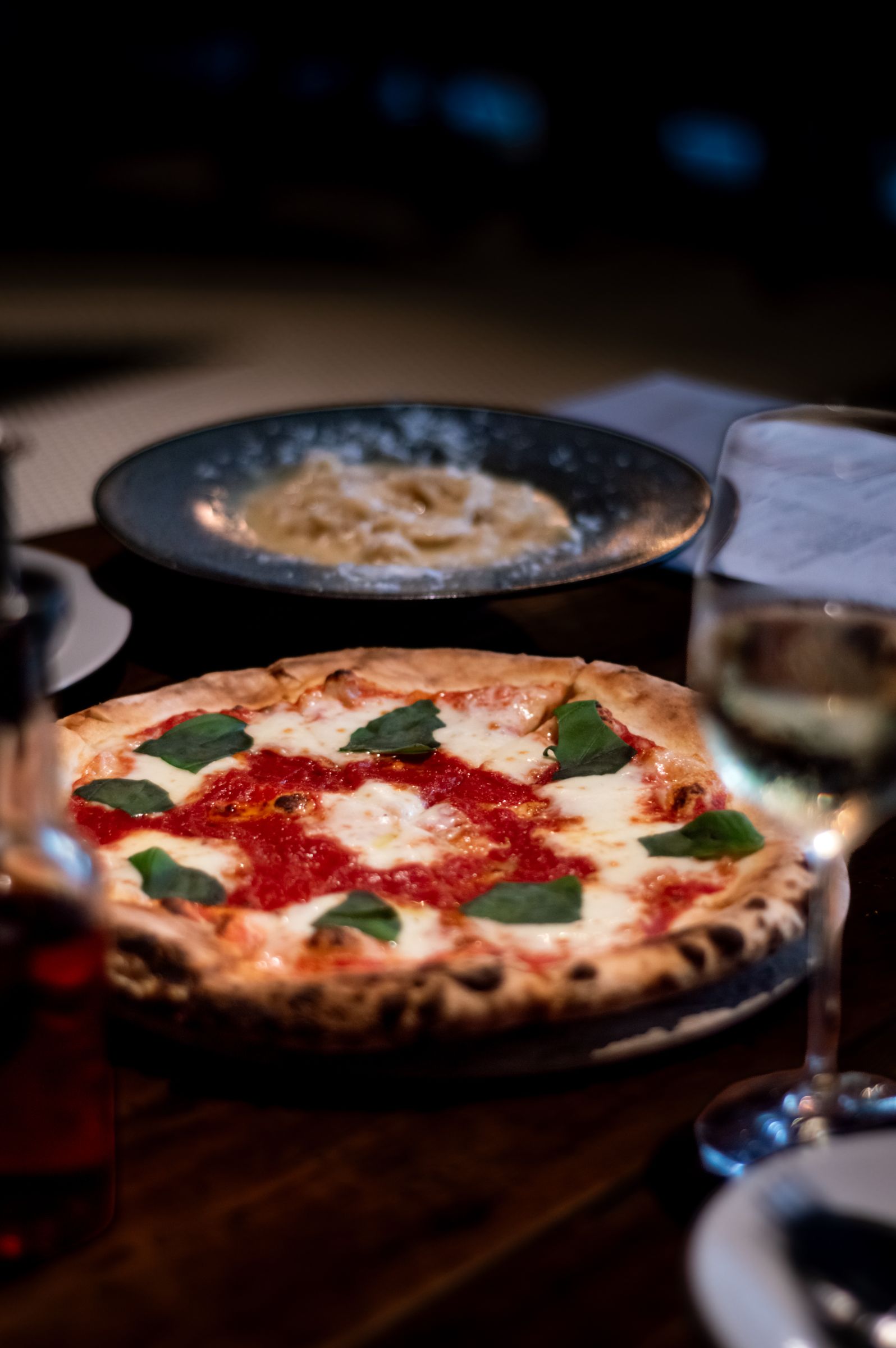 A margherita pizza on a restaurant table lit by candles
