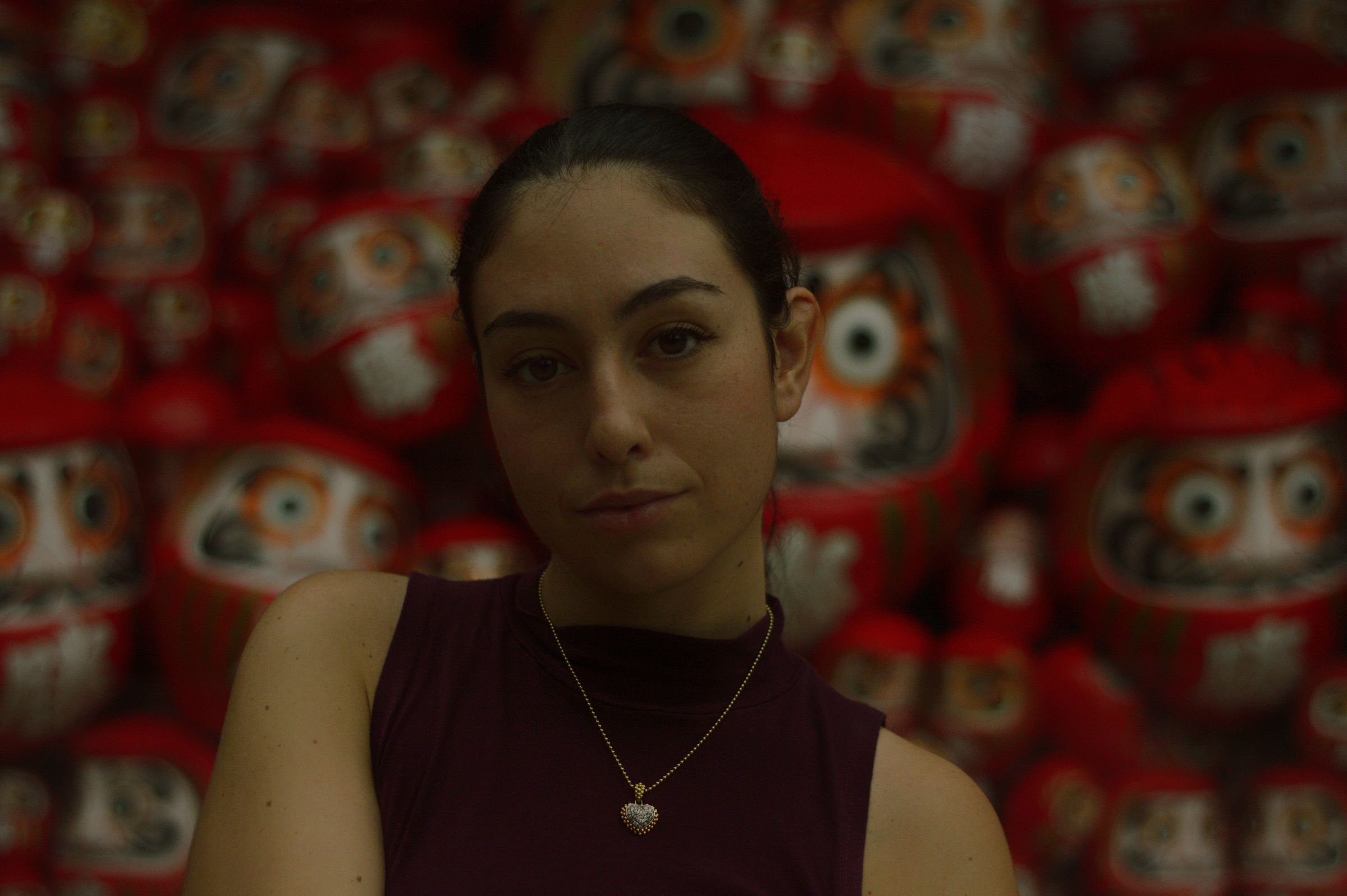 A woman in front of shelves of red daruma dolls